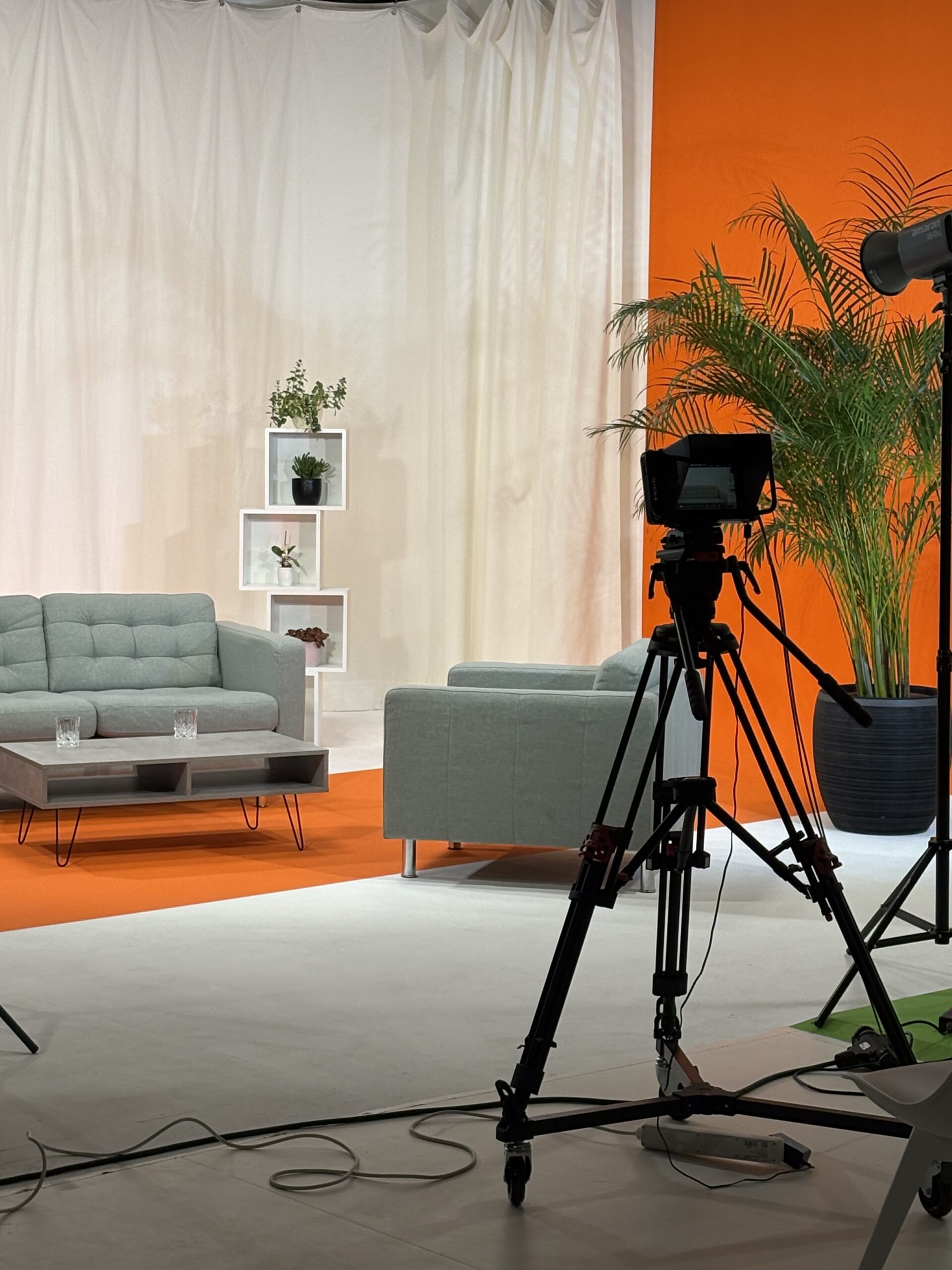 Professionelles Fernsehstudio mit Kamera und Sofas.
